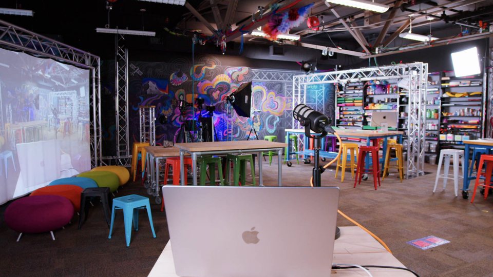 The Learning Lab studio: colourful stools, lighting rigs, shelves of craft supplies and a laptop